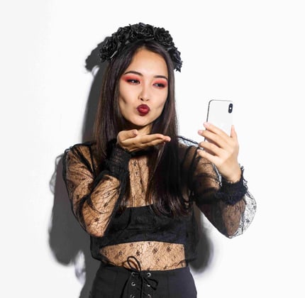 portrait-stylish-asian-female-blogger-with-gothic-makeup-halloween-costume-sending-air-kiss